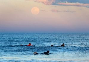 The super moon looms over surfers in Sydney, Australia